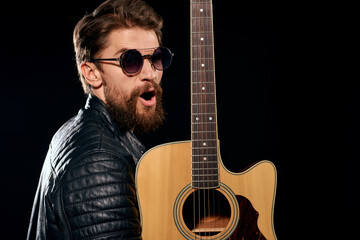 A man with a guitar in his hands leather jacket music performance rock star modern style dark background