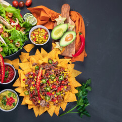 Hispanic mexican food, nachos, guacamole, meat tacos on dark background