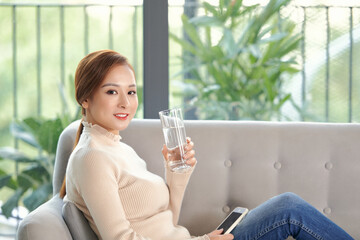 Girl drinking water sitting on a couch at home