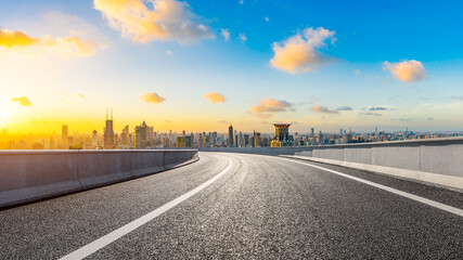 Empty asphalt road and Shanghai skyline with buildings at sunset.