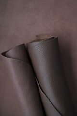 Brown genuine leather roll.real leather set. Leather in rolls on a  brown leather surface.Hobby and...