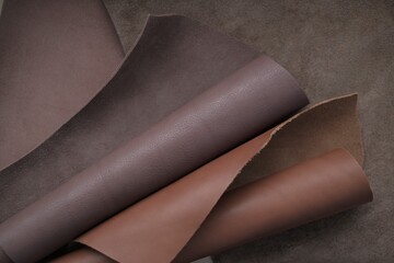 Brown genuine leather roll.real leather set. Leather in rolls on a blurred brown leather surface.Hobby and craft material. leather texture.Material for shoes, clothing and accessories