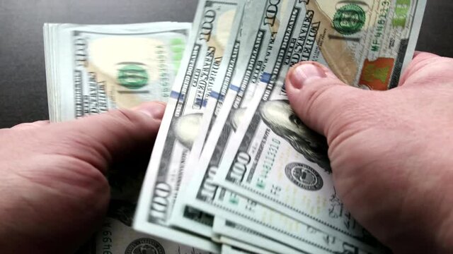 Men's hands count stack of hundred-dollar US bills in close-up. Concept of enrichment and financial transactions with fiat paper cash