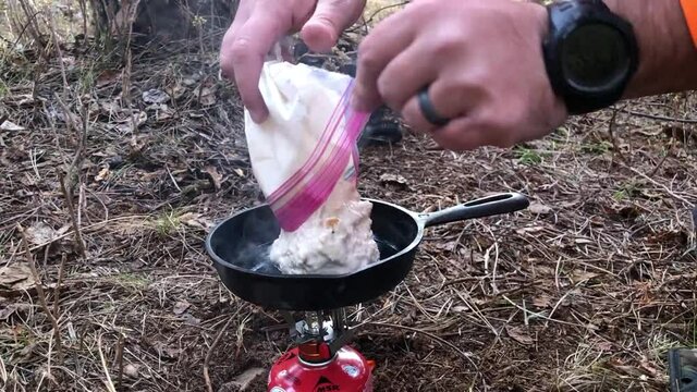 Cooking bannock with a cast iron pan over a small gas powered camping stove.