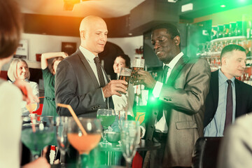 Portrait of African and Caucasian men having fun and talking at the corporate party