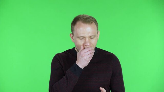 Portrait of a middle aged men clapping his hands, yawning, boring, uninteresting. Unshaven male in a black red sweater posing on a green screen in the studio. Close up.
