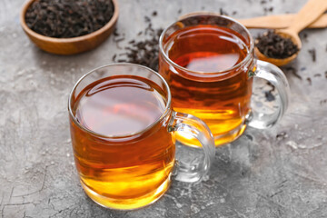 Cups of tea and dry leaves on dark background, closeup