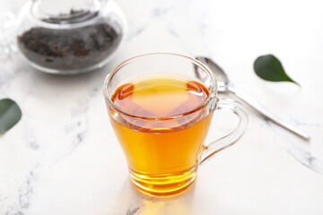 Cup of tea and dry leaves on light background