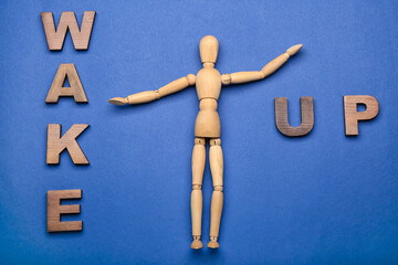 Wooden mannequin with words WAKE UP on color background