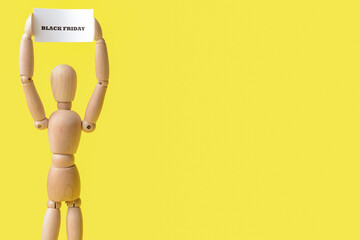 Wooden mannequin and card with text BLACK FRIDAY on color background