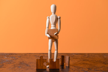Wooden mannequin with puzzles on color background