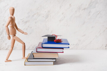 Wooden mannequin with books on light background