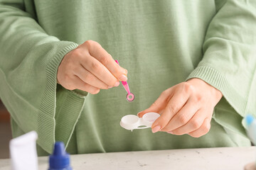 Woman taking contact lens from container, closeup