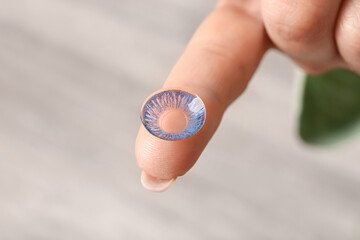 Female hand with contact lens on light background
