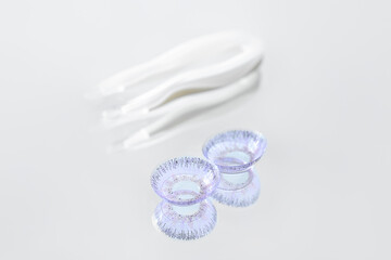 Contact lenses and tweezers on light background