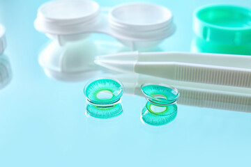 Contact lenses, container and tweezers on color background