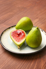 Plate with fresh green figs on wooden background