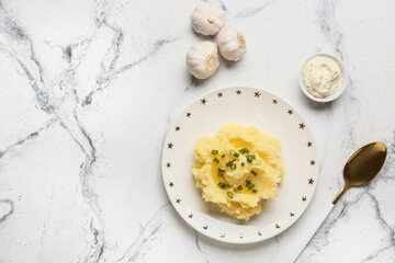 Plate with tasty mashed potatoes and garlic on light background