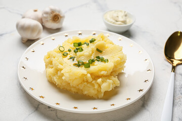 Plate with tasty mashed potatoes and garlic on light background