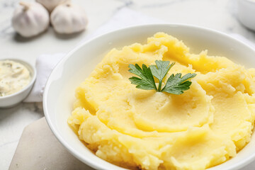 Plate with tasty mashed potatoes and garlic on light background