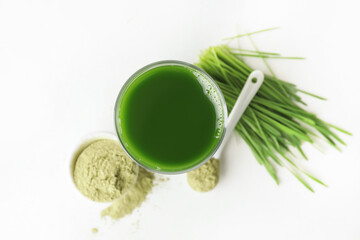 Glass with fresh wheatgrass juice and powder on white background