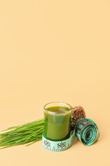 Fototapeta premium Glass with fresh wheatgrass juice and measuring tape on color background