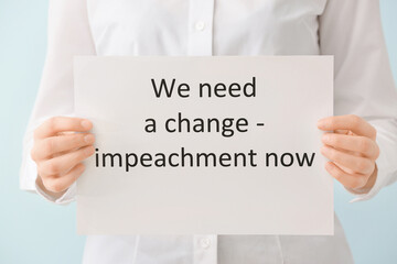 Woman holding paper with text WE NEED A CHANGE - IMPEACHMENT NOW on color background