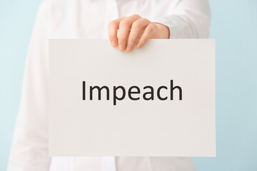 Woman holding paper with text IMPEACH on color background