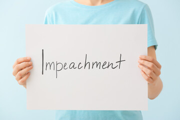 Woman holding paper with text IMPEACHMENT on color background