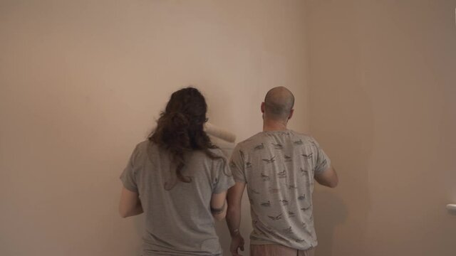 Young european couple painting room wall in emty house in cambridge england