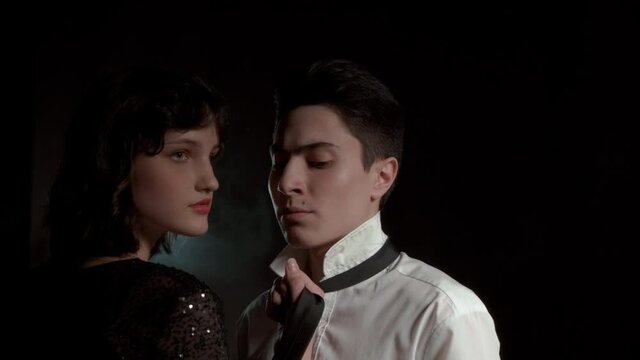 Dramatic portrait of a couple. Female domination concept. Diverse perspective, close-up, men and women. They stand in a dark room with smoke in the background and some flashlight.