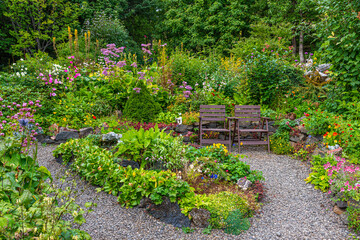 Two wooden chairs in a flourishing garden
