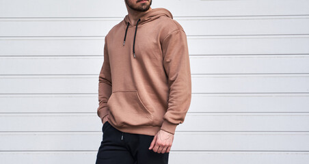 Man is standing in brown hoodie and dark pants. Man is wearing light suede stylish long sleeve...