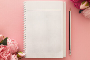 Blank notepad and pink peonies on a pink table background, background. Business concept, study. Women's Day. Flat lay, top view, copy space