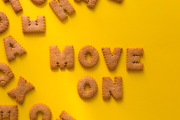 Word Move on in the middle of the picture made of crunchy cookies in form of English alphabet letters, textured bright yellow background, health, dieting and medical concept. Copy space, big letters