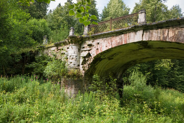 Fototapeta na wymiar Big white stone bridge in the park of the Serednikovo estate on a summer day