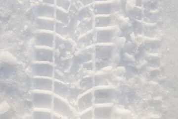 Trail from wheel of car in snow during warm sunny winter day