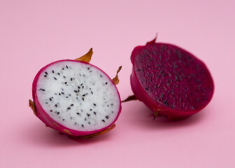 Red and pink halves of a dragon fruit with red and white flesh. The pitaya fruit is low in...