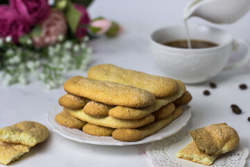 Biscuit cookies savoyardi, coffee and flowers on a white marble background