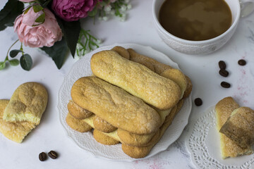 Biscuit cookies savoyardi, coffee and flowers on a white marble background