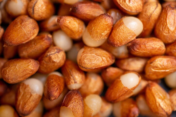 Background of peeled pine nuts from Siberia, milky color with a yellow dry skin. 