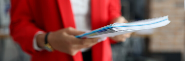 Woman in red jacket holds documents in her hands closeup. Prestigious business education concept.