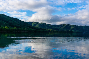 Fototapeta na wymiar 湖の湖面に反射する青い空と緑の山なみ