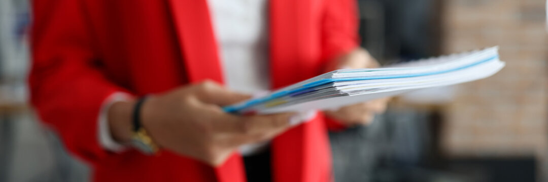 Woman in red jacket holds documents in her hands closeup. Prestigious business education concept.