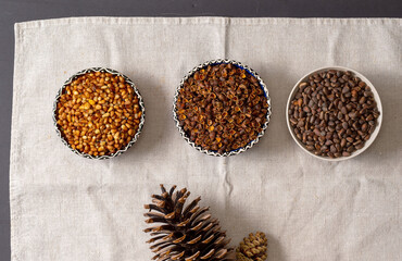 Three round bowls with Siberian pine nuts. Peeled nut kernels, their shells, whole cone grains.