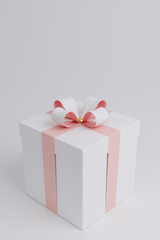 Realistic white gift box with pink ribbons and white and pink bow. Decorative gold element on the lid. Festive object for vertical poster, holiday banner, flyer, greeting card. 3D illustration.