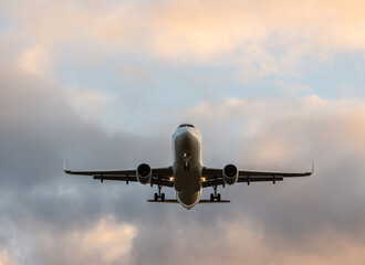 Commercial airplane jetliner flying above dramatic clouds in beautiful light. Travel concept.