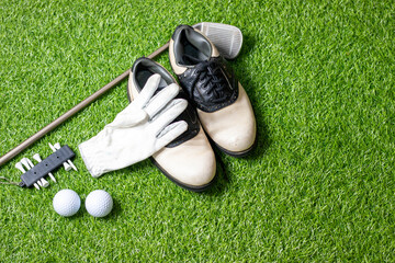 Golf ball with golf shoes and glove on green grass