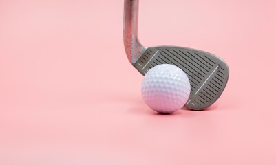 Golf club and golf ball are on pink background