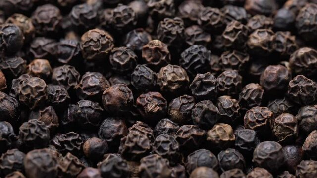 Close-up video of a slowly rotating black pepper
